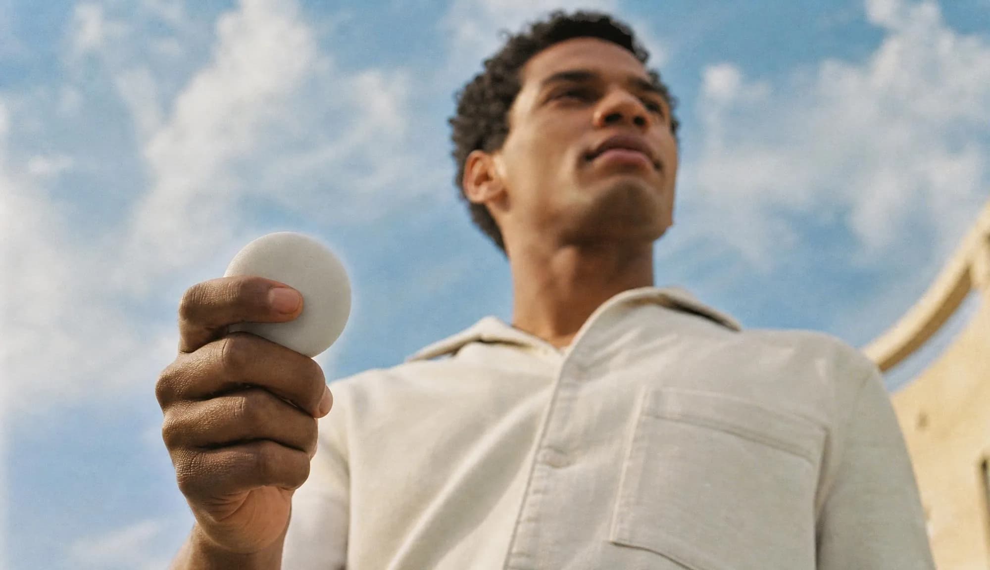 Low-angle portrait with the device held against the sky.
