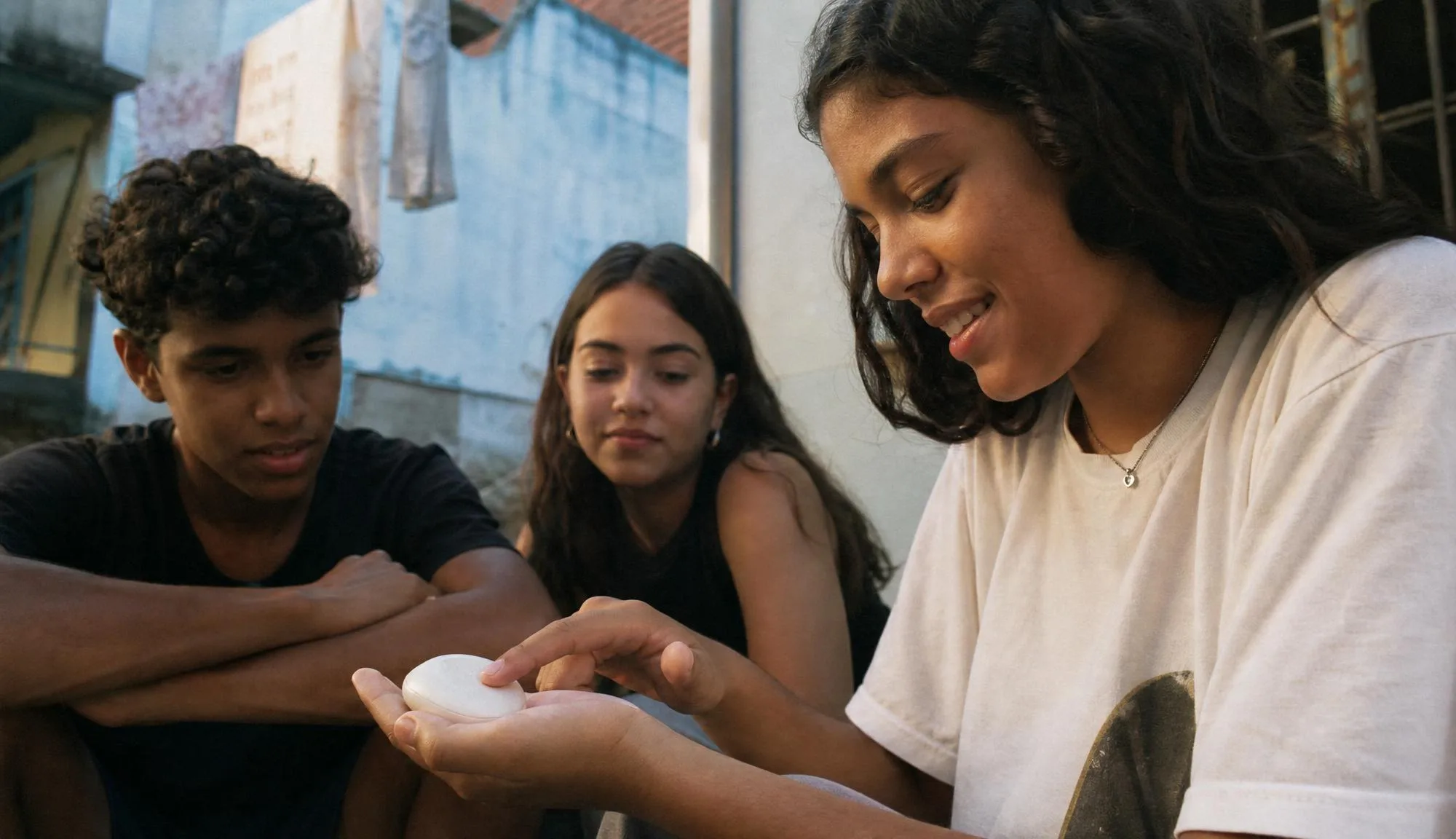 Three young people gathered around the device outdoors.